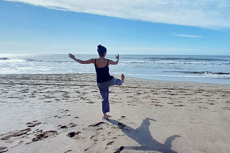 En person gör yoga på stranden